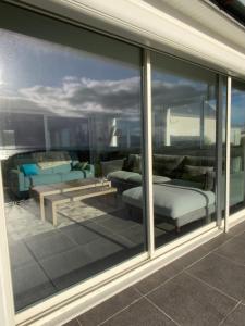 a glass window of a balcony with a bed and couch at Superbe Villa Face à L'Océan in Plouhinec