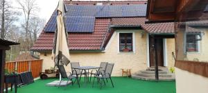 eine Terrasse mit einem Tisch und Stühlen sowie ein Haus mit Sonnenkollektoren in der Unterkunft Ubytování U Potoka in Kunratice