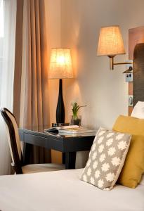 a desk in a hotel room with a bed and a lamp at Castel Maintenon Hôtel, Restaurant & Spa in Maintenon