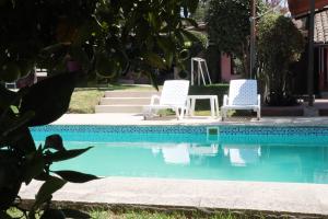 two white chairs sitting next to a swimming pool at Hotel Venus de Valdivia Aeropuerto in Tababela