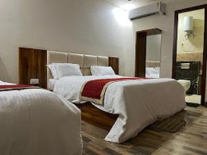 a hotel room with two beds and a mirror at Hotel Taj Sarovar By WB Inn in Agra