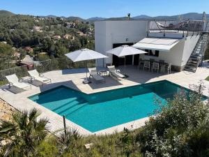 a pool with chairs and umbrellas on top of a house at Luxury Sitges Hills Villa in Olivella