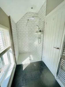 a white bathroom with a shower and a window at Entire 2 bed cottage - Llangwm in Llangwm