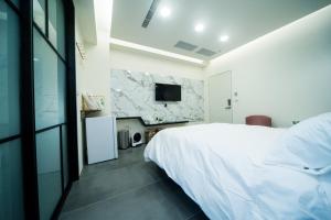 a bedroom with a white bed and a tv at 會呼吸的房507-睡虎尾-電梯bnb in Huwei