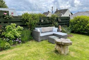 a garden with a couch and a stump in the grass at Entire 2 bed cottage - Llangwm in Llangwm