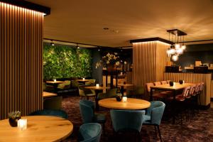 a restaurant with wooden tables and chairs and plants at Hotel Arrows in Uden