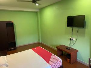 um quarto verde com uma cama e uma televisão de ecrã plano em Select Residency em Calecute