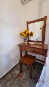 a table with a mirror and a vase with flowers on it at Anna Garden Sidari in Sidari