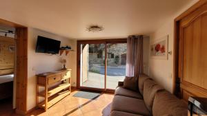 a living room with a couch and a sliding glass door at Chalet Coquelicot confort cosy au coeur du village de Saint Martin in Saint-Martin-de-Belleville