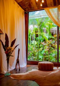 a room with a window with a giraffe and a vase of flowers at Ocho Artisan Bungalows in Tamarindo