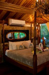 a bedroom with a canopy bed with a television above it at Ocho Artisan Bungalows in Tamarindo
