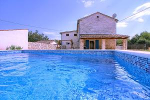 Una gran piscina azul frente a una casa en Cozy istrian stone villa Sasso with private pool, en Petehi