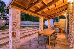 Un patio al aire libre con una mesa y sillas de madera. en Cozy istrian stone villa Sasso with private pool, en Petehi