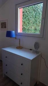 een dressoir met een lamp en een raam erop bij Una terrazza sul lago in Argegno
