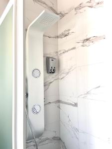 a shower in a bathroom with white marble at Hostal El Caprichito Marbella in Marbella
