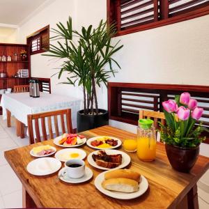 - une table en bois avec des aliments pour le petit-déjeuner et du jus d'orange dans l'établissement Pousada União, à Jericoacoara