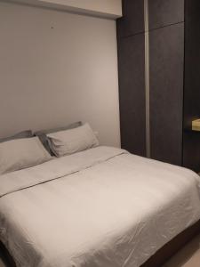 a bed with white sheets and pillows in a room at Hyve Soho Suite - Netflix in Cyberjaya