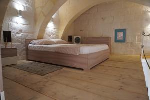 a bedroom with a bed and a stone wall at Il-Mezzanine in Cospicua