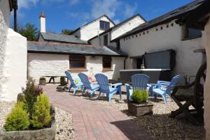 a patio with blue chairs and a table in front of a building at SAUNTON SUNSHINE COTTAGE 3 Bedrooms in Braunton