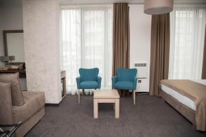 een hotelkamer met een bed en twee blauwe stoelen bij Apartman V&V in Zlatibor