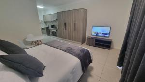 um quarto com uma cama e uma televisão de ecrã plano em The Aura em Roodepoort