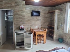 a dining room with a table and a tv on a brick wall at Pousada Mar & Sol de Camburi in Camburi