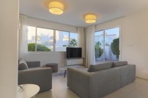 a living room with two couches and a flat screen tv at Pernera Gardens Villa in Protaras