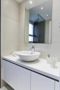 a white bathroom with a sink and a mirror at Pernera Gardens Villa in Protaras