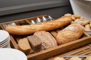 a wooden tray filled with different types of bread at Hotel Akwawit in Leszno