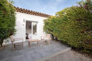 patio z 2 krzesłami i stołem obok żywopłotu w obiekcie Villa B w mieście Salernes
