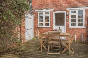 a wooden table and chairs in front of a brick building at Pelican Cottage in Aldeburgh