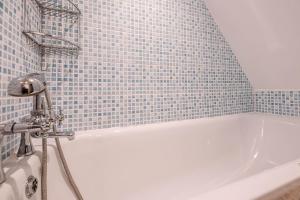 a bathroom with a white tub with a blue tile wall at Pelican Cottage, Aldeburgh in Aldeburgh +22 photos