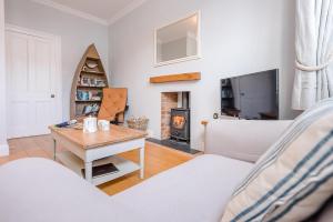 a living room with a couch and a table and a fireplace at Pelican Cottage, Aldeburgh in Aldeburgh