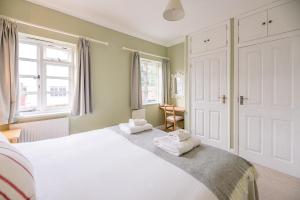 a bedroom with a large white bed with towels on it at Pelican Cottage in Aldeburgh