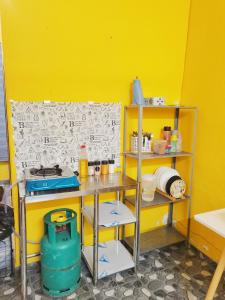 a kitchen with a yellow wall and a table and shelves at Bluewave Sea Out Seaview Homestay in Kuah