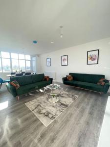 a living room with two green couches and a table at Flitwick Luxury 3 Bedroom Apartment in Flitwick