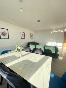 Flitwick Luxury 3 Bedroom Apartment في فليتويك: غرفة مع طاولة مع كراسي و إناء من الزهور