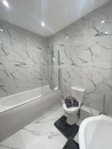 Flitwick Luxury 3 Bedroom Apartment في فليتويك: حمام مع مرحاض وحوض استحمام ومغسلة