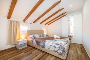 a bedroom with white walls and a bed and wooden floors at Bistra Pakoštane Apartments in Pakoštane