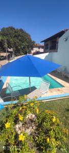 una sombrilla azul y sillas junto a la piscina en Linda casa de condomínio com piscina, na Praça 21, en Porto de Galinhas