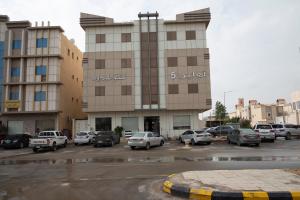 un estacionamiento con autos estacionados frente a un edificio en Ahlin Suites 5 en Riad