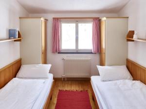 two beds in a small room with a window at Adele (704 De) in Lenzerheide