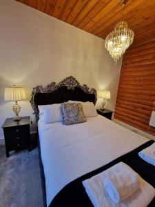 1 dormitorio con 1 cama grande y lámpara de araña en Kaoglen Warren - Pet friendly - Hot Tub - Cairngorms, en Blairgowrie