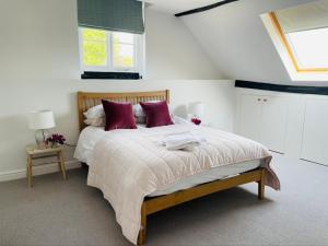 a bedroom with a large bed with purple pillows at Barn Cottage -Westerlands in Graffham