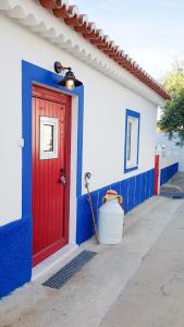 un edificio rojo y azul con una puerta roja en Casa dos chocalhos-Piscina-Perto Praia Fluvial-Vista incrível e sossego, en Mértola