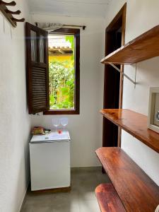 a room with a small refrigerator and a window at Pousada Oceano in Caraíva