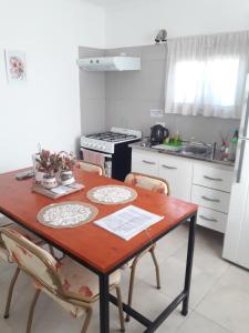 y cocina con mesa de madera, sillas y fogones. en Departamento para 4 personas en Tandil en Tandil