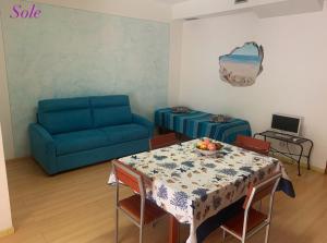Una sala de estar con una mesa y un sofá azul. en Casa Sole e Luna, en Canneto