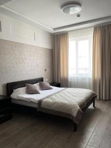 a bedroom with a bed and a large window at Sun Lidia in Chernivtsi