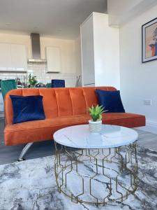 un sofá naranja con almohadas azules y una mesa en Flitwick Luxury Apartment, en Flitwick